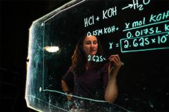 Chemistry student writes on glass board