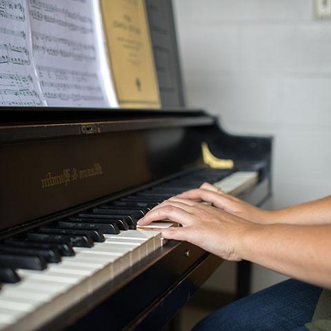 Susannah White plays piano in practice room