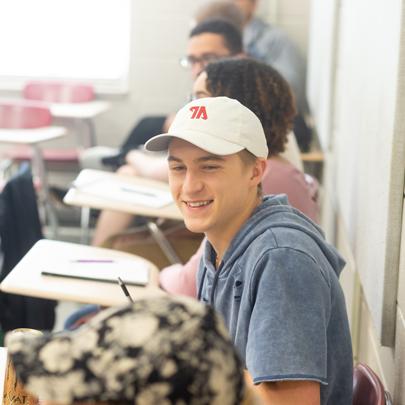 Student in 365bet ball cap sitting in a classroom